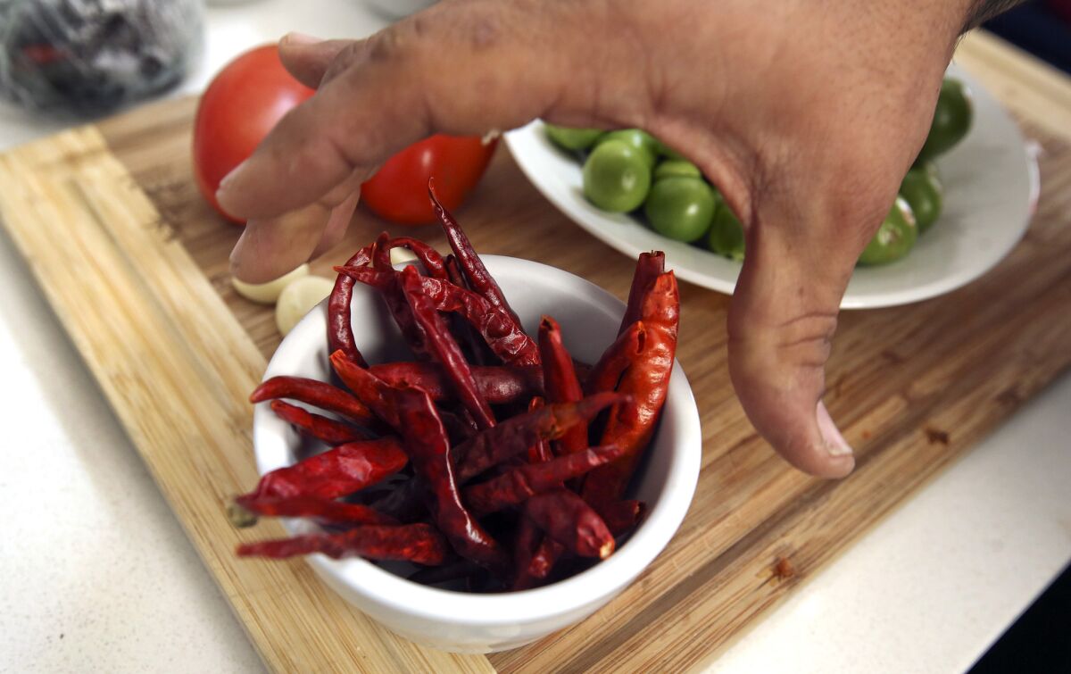 Wes Avila of Guerrilla Tacos grabs a cup of peppers, while preparing to make his sweet potato breakfast tacos.