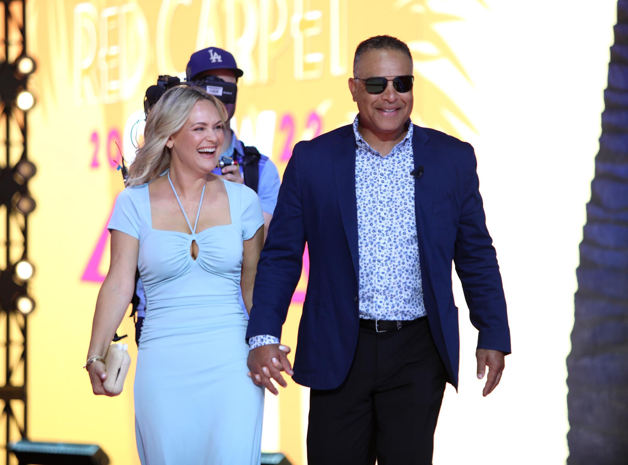 Dodgers manager Dave Roberts in a blue and black suit arrives with his wife at the 2022 MLB All-Star Game Red Carpet Show.