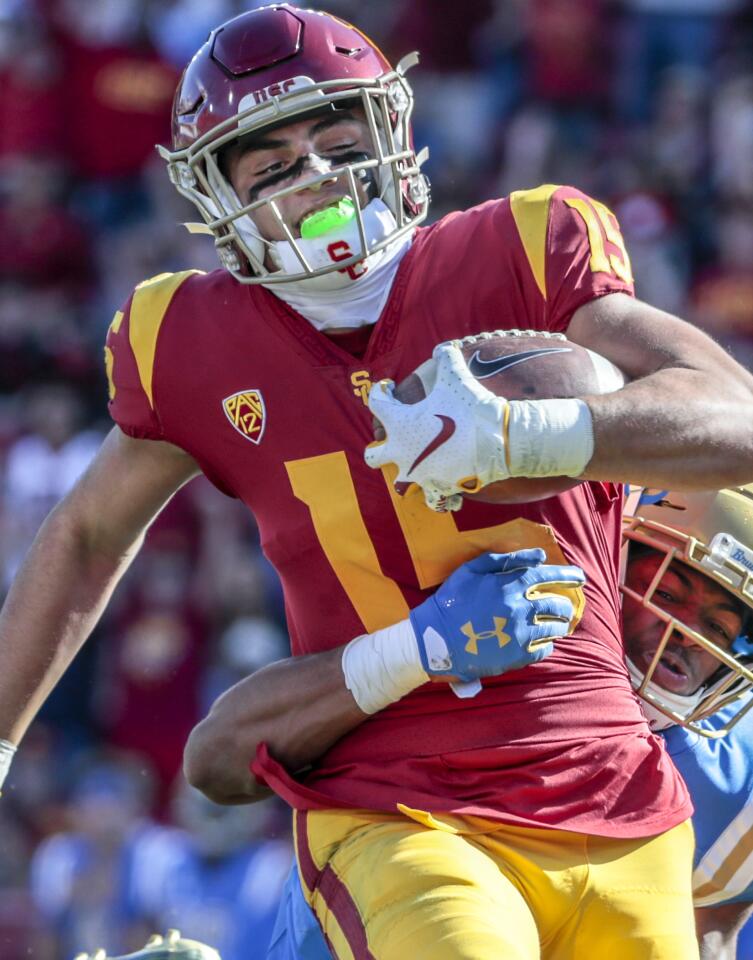 USC wide receiver Drake London (15) is dragged down from behind by UCLA defensive back Stephan Blaylock after a long catch and run in the first half at the Coliseum on Saturday.
