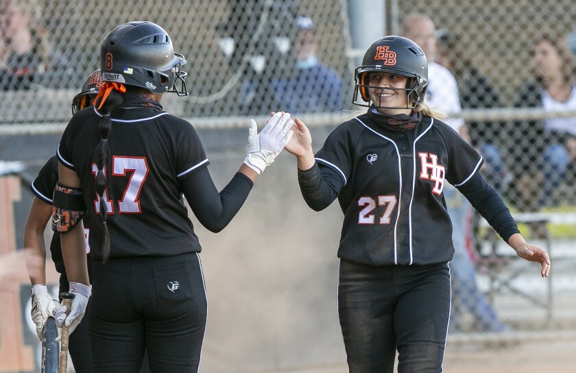 Huntington Beach's Jaylene Duarte, left, high-fives Zoe Nakutis during a softball game against Marina on April 28.