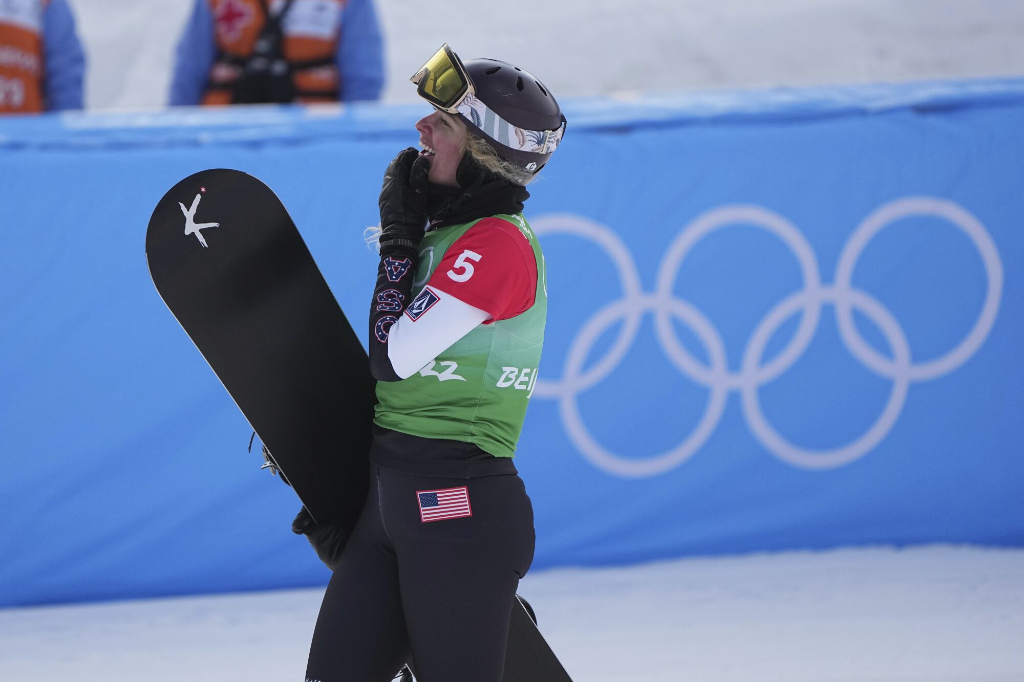 Lindsey Jacobellis smiles and carries her snowboard at the 2022 Olympics.