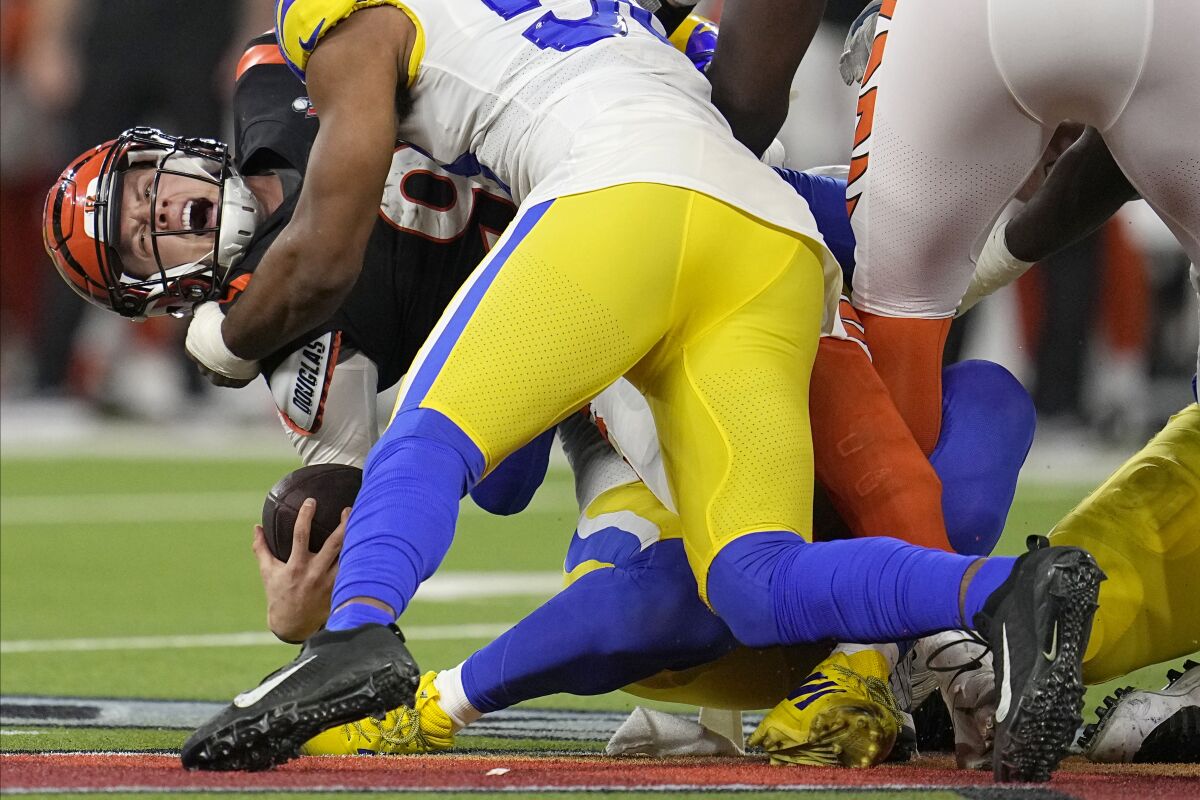 Cincinnati Bengals quarterback Joe Burrow, left, is sacked by Los Angeles Rams outside linebacker Justin Hollins during the second half of the NFL Super Bowl 56 football game Sunday, Feb. 13, 2022, in Inglewood, Calif. (AP Photo/Marcio Jose Sanchez)