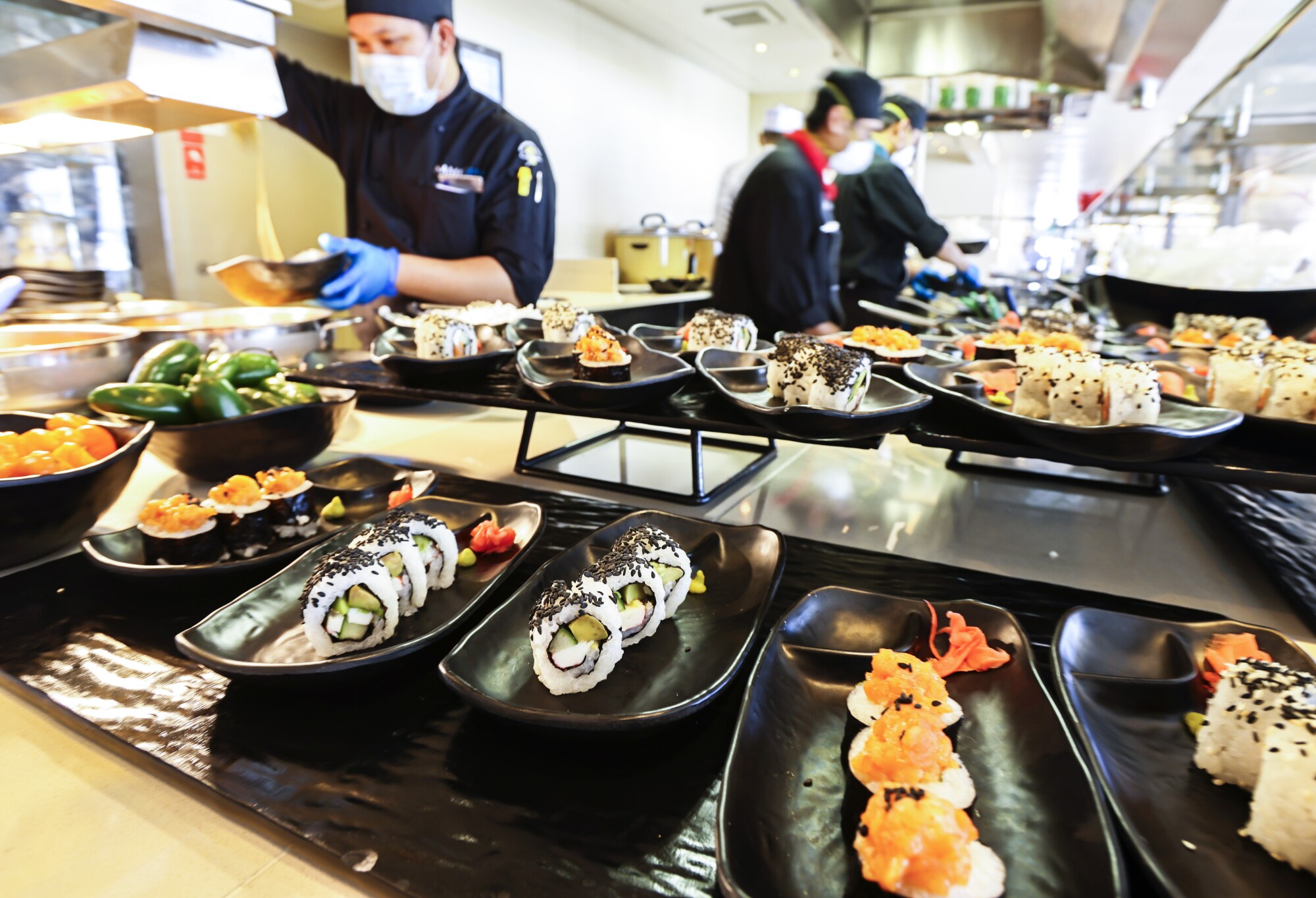 Crew members serve lunch for staff at a sushi bar on the Lido Deck of the Holland America Line cruise ship Koningsdam.