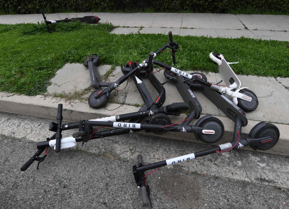 Scooters lie on a Los Angeles sidewalk. Collecting, charging and redeploying the scooters are responsible for nearly half of their environmental impact.