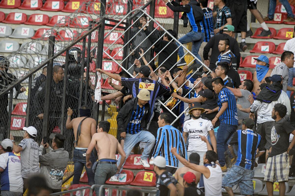 Fans hold a metal barrier during a Mexican soccer league match between the host Queretaro and Atlas from Guadalajara.
