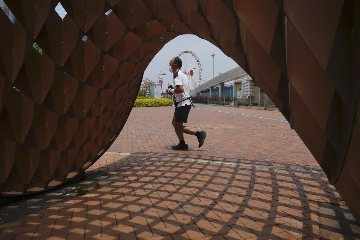 A man jogs in a park in Hong Kong, Thursday , May 5, 2022. Hong Kong on Thursday reopened beaches and pools in a relaxation of COVID-19 restrictions, while China's capital Beijing began easing quarantine rules for arrivals from overseas. (AP Photo/Kin Cheung)