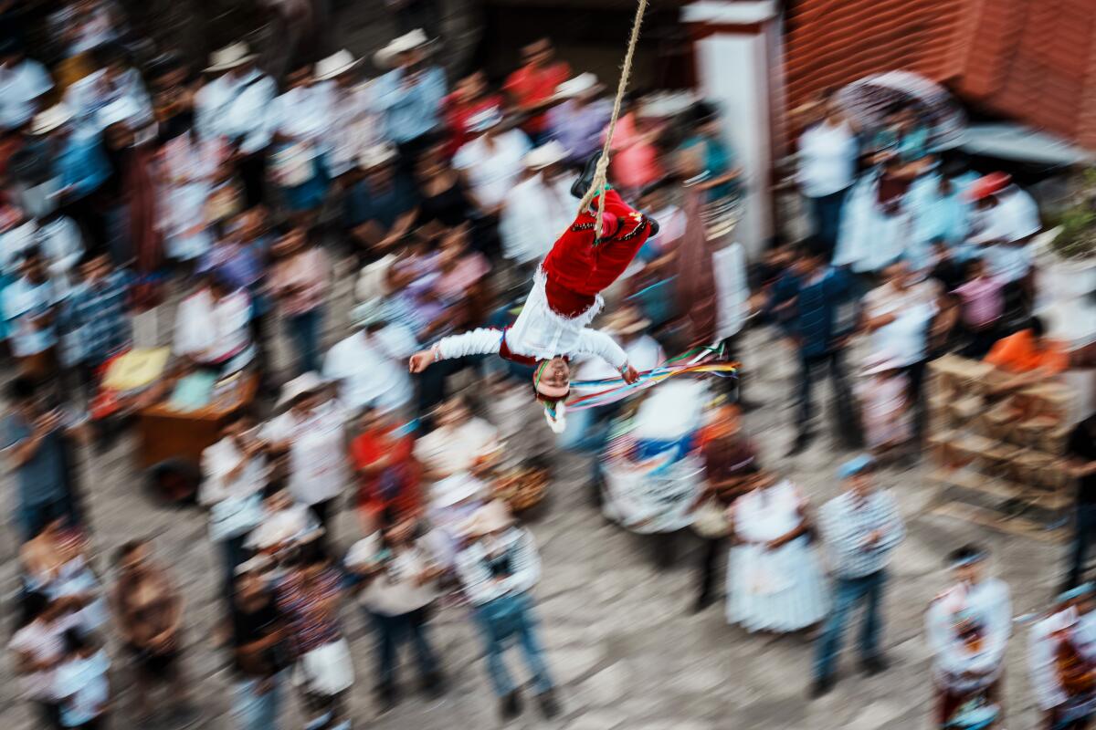 A Volador closes his eyes as he flies around the tree tied to a rope