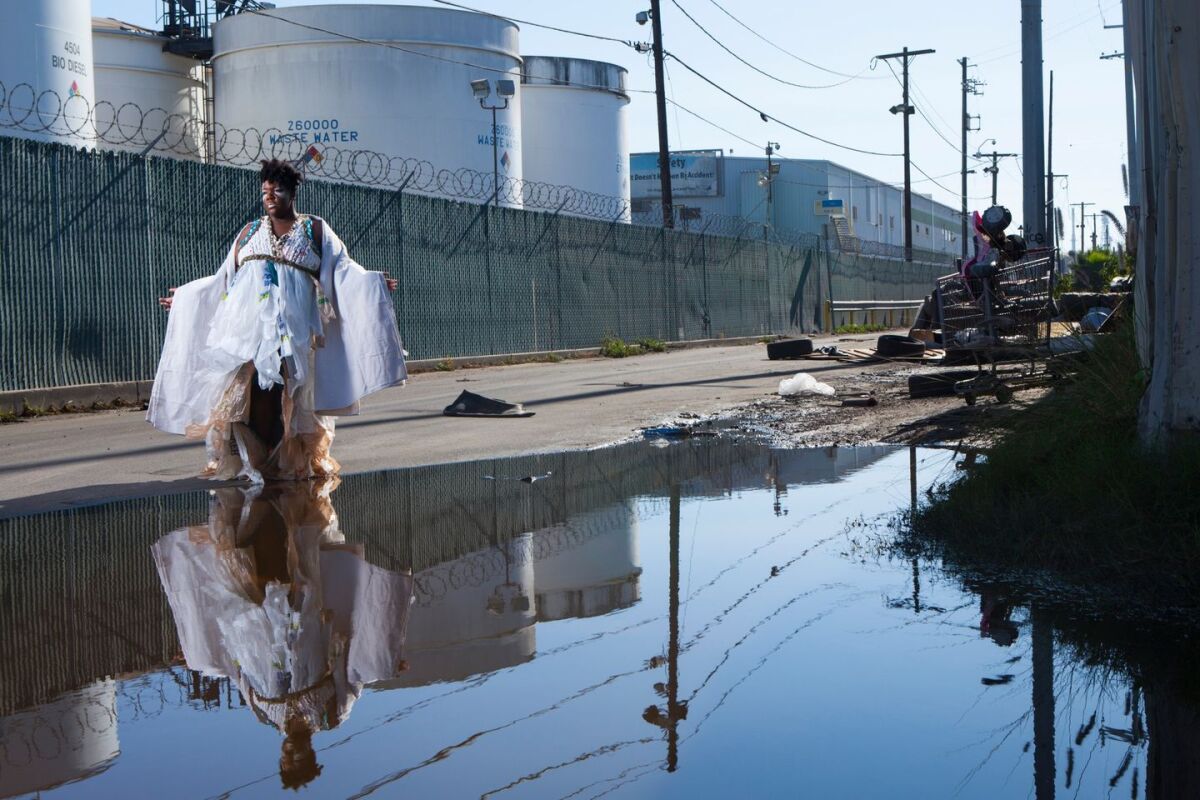 A figure walks along a street reflected in water.