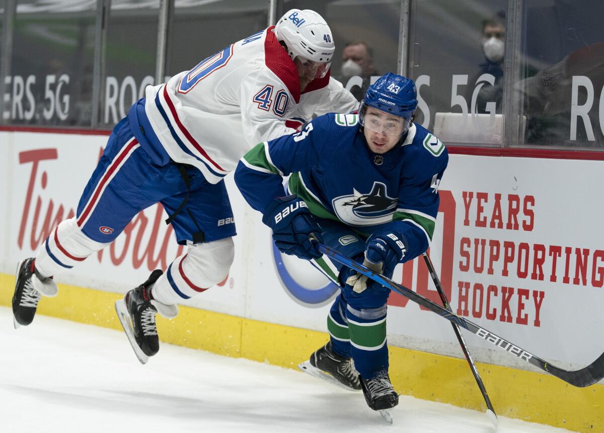 Vancouver Canucks defenseman Quinn Hughes (43) fights for control of the puck with Montreal Canadiens right wing Joel Armia (40) during first-period NHL hockey game action in Vancouver, British Columbia, Monday, March 8, 2021. (Jonathan Hayward/The Canadian Press via AP)