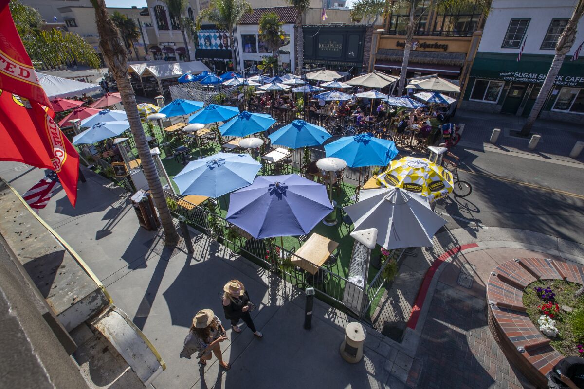 Patrons dine under umbrellas and other portable shelters on Main Street in Huntington Beach on July 28.
