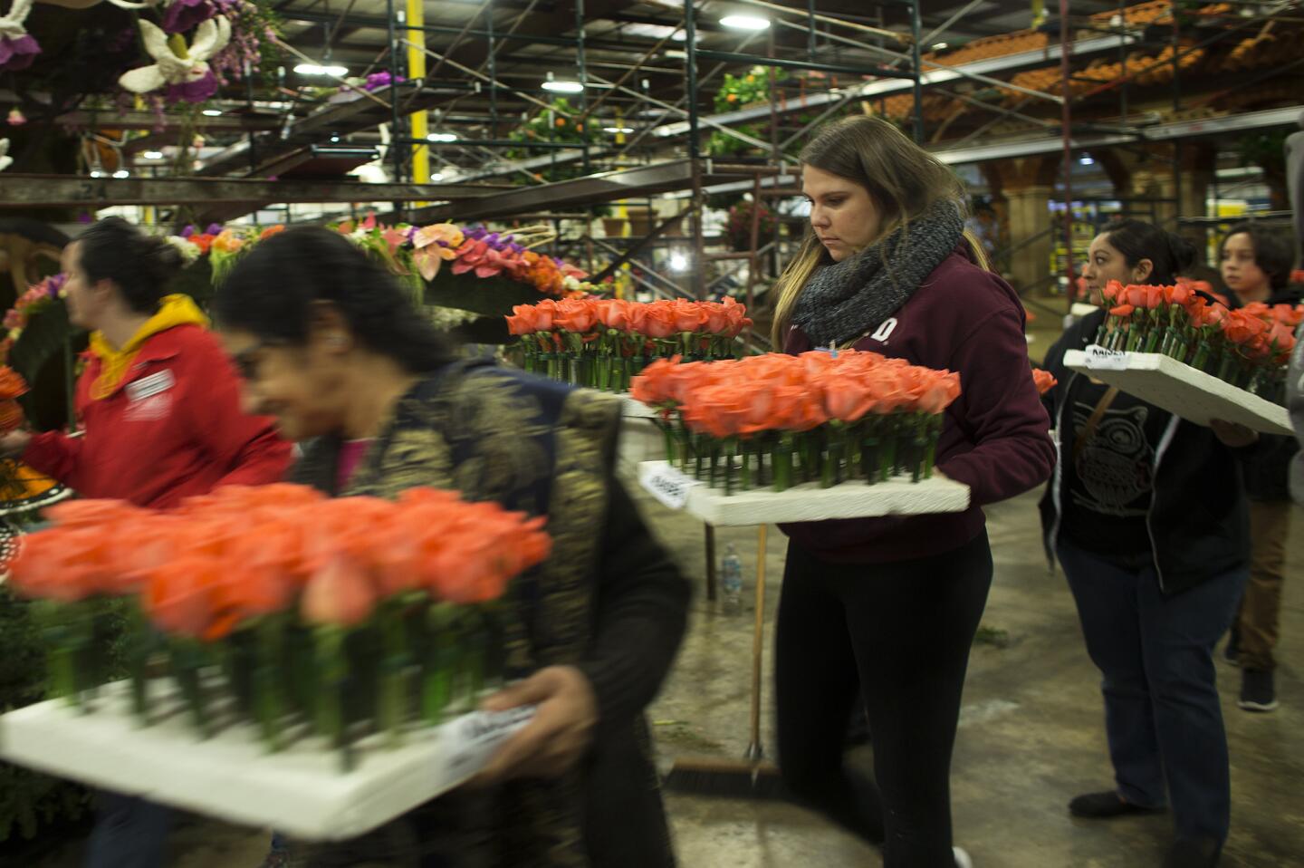 Workers carry fresh flowers to finish floats for the Rose Parade in a warehouse in Irwindale, Calif.