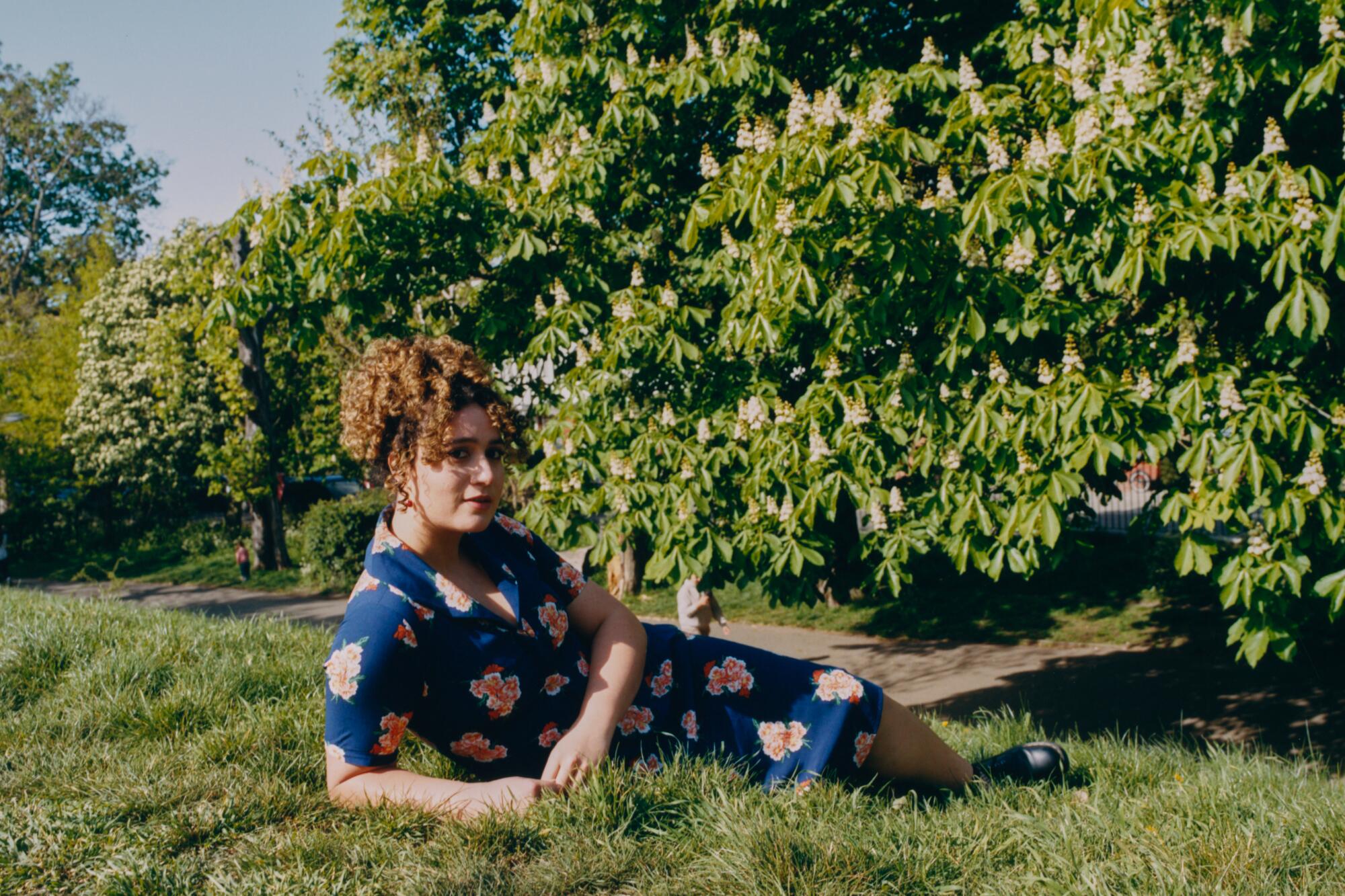 Rose Matafeo sits in the grass for a portrait.