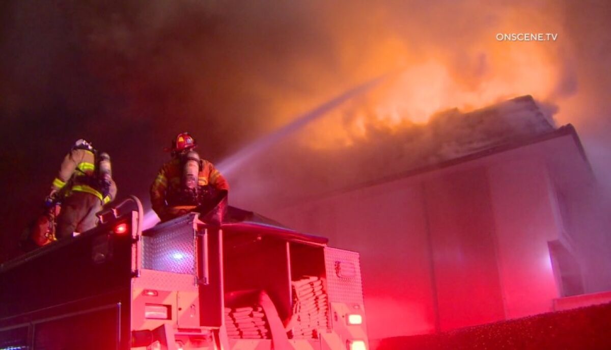 Firefighters spray water onto the flames erupting from the roof of one of the buildings at the Del Mar Beach Club in Solana Beach on Tuesday night.