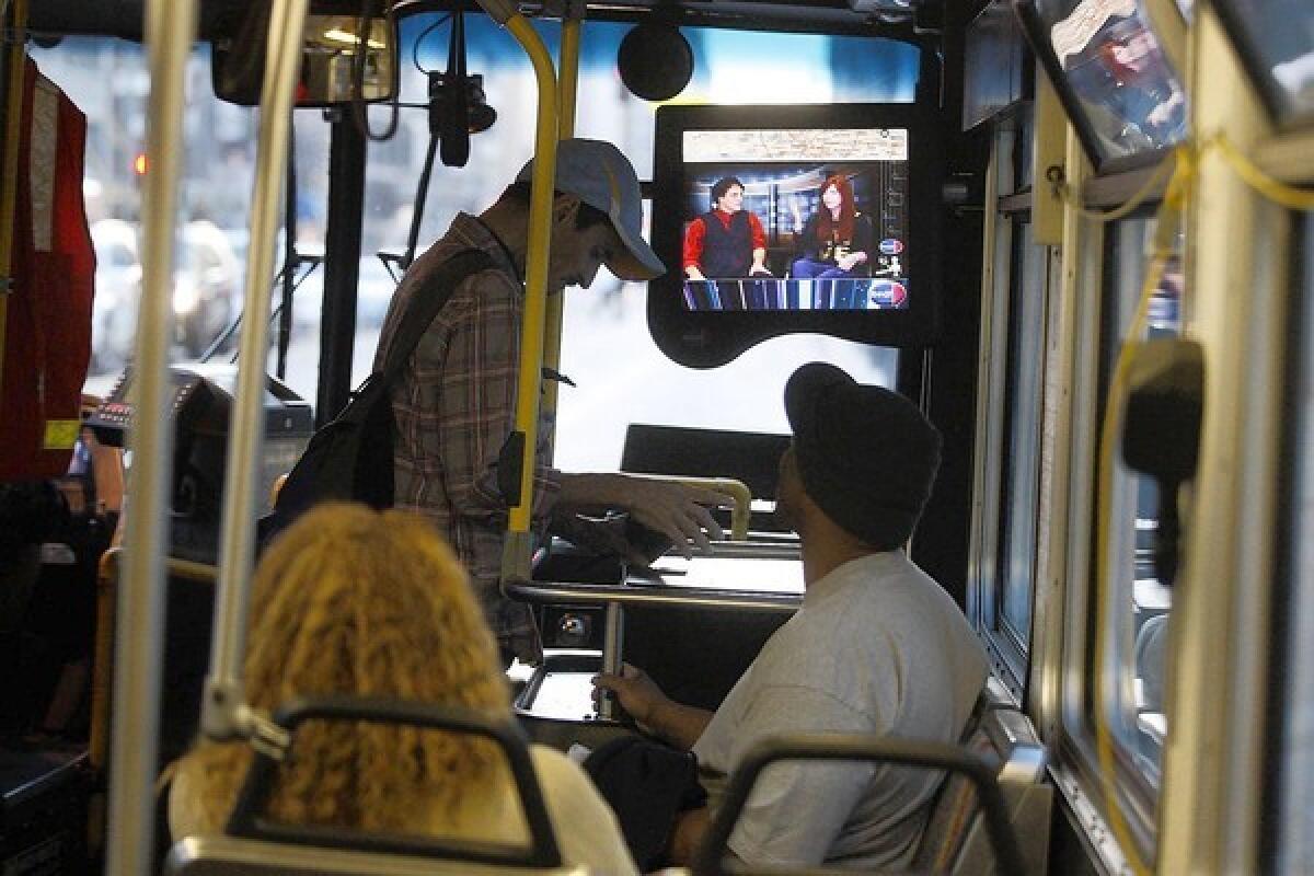 As riders ride a Los Angeles County Metropolitan Transportation Authority bus in downtown Los Angeles, television monitors show a daily newscast, produced by KNBC-TV Channel 4, on October 22, 2013 in downtown Los Angeles.