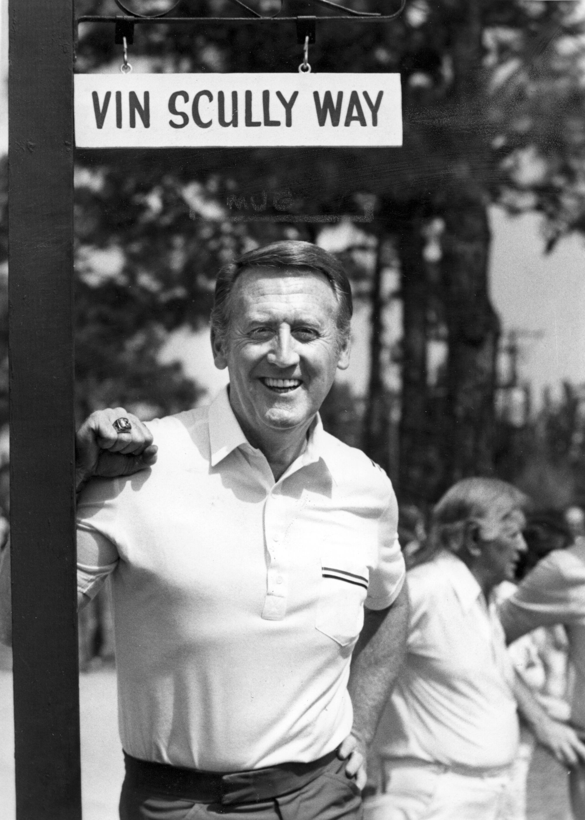 Vin Scully stands under a "Vin Scully Way" street sign at the Dodgertown spring training facility in Vero Beach, Fla.