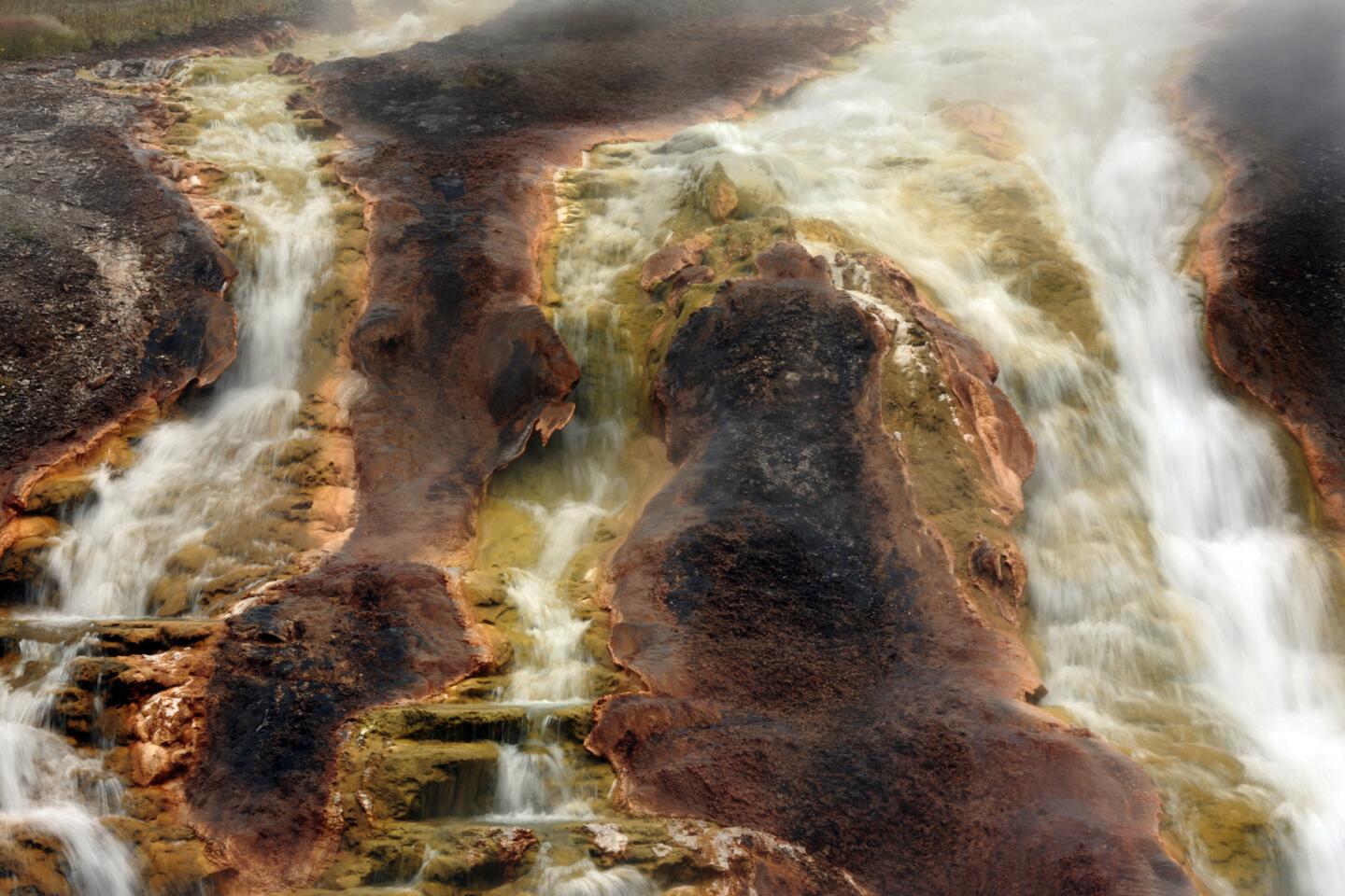 Hot water flows over rocks stained by bacteria, microbes and minerals into the river in the Midway Geyser Basin, where the Excelsior Geyser, Grand Prismatic Spring and Turquoise Pool are the star attractions in Yellowstone National Park.