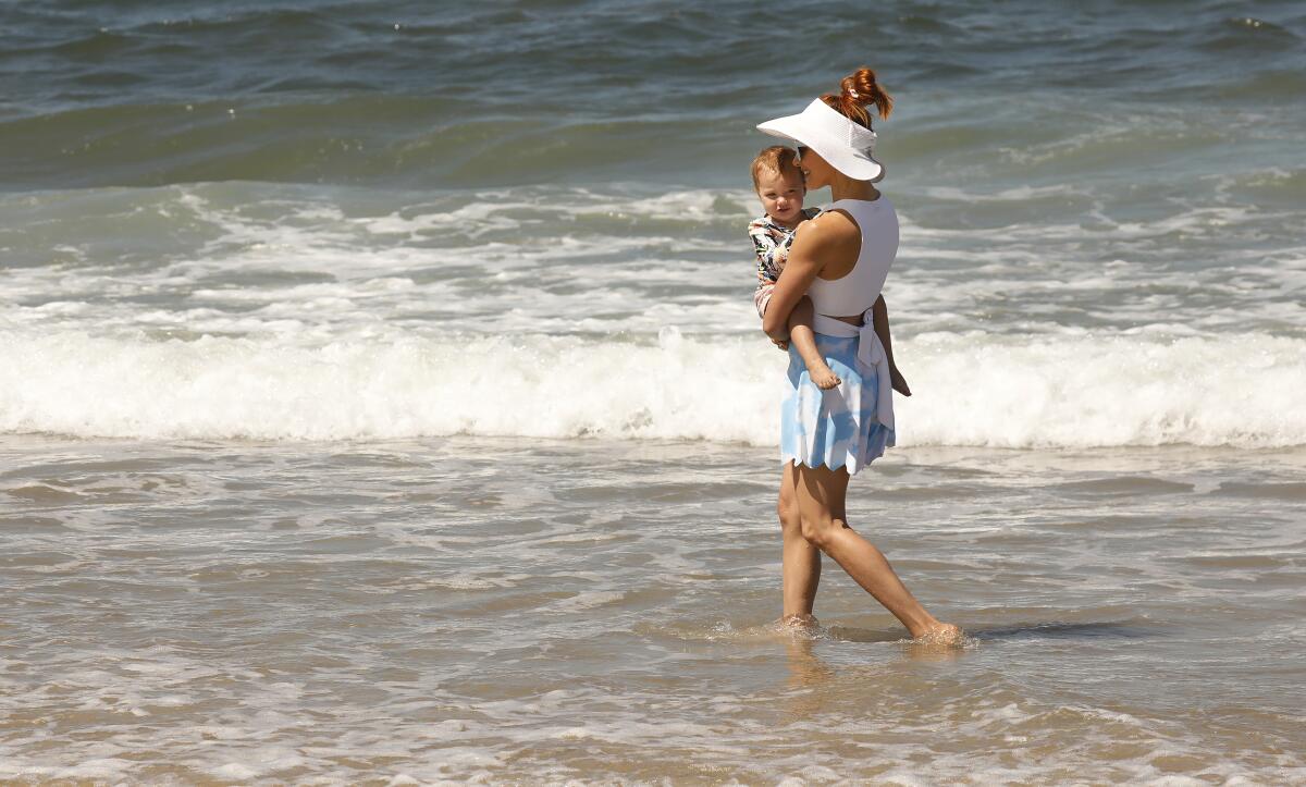 A woman carries a toddler in the surf at Playa del Rey.