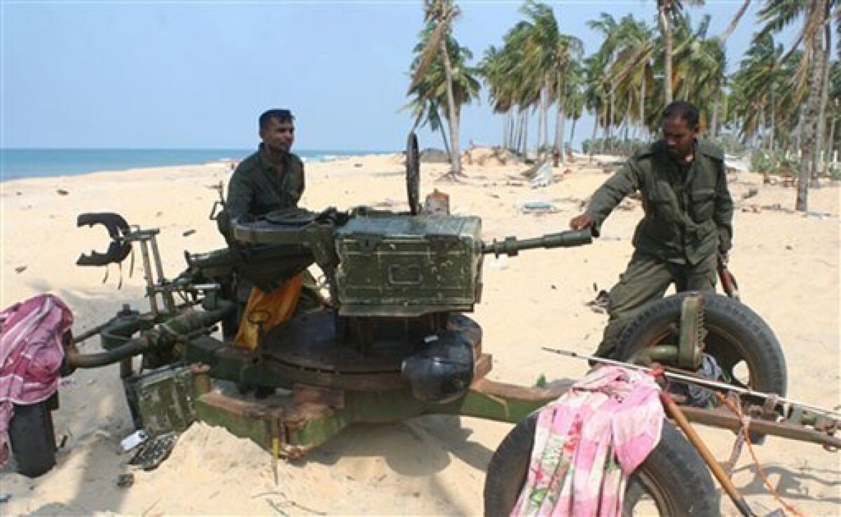 In this Sunday, May 10, 2009 handout photo made available by the Sri Lankan army, soldiers check a weapon used by the Tamil Tiger rebels against security forces in the war zone, in Mullivaaykaal, Sri Lanka. (AP Photo/Sri Lankan army, HO)