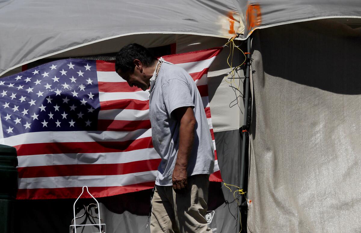 A man standing in front of an American flag that hangs from a tent.