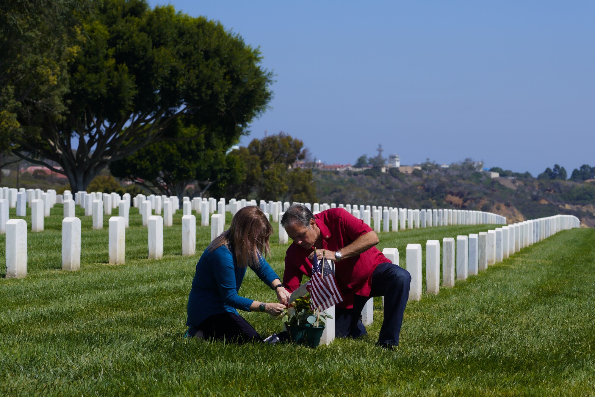 Kenny Necochea Sr. and Lori Necochea place flowers at a headstone