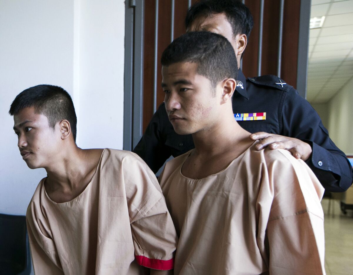 FILE - In this Dec. 24, 2015 file photo, Myanmar migrants Win Zaw Htun, right, and Zaw Lin, left, both 22, are escorted by officials after their guilty verdict at court in Koh Samui, Thailand. The two were convicted of killing 24-year-old British David Miller and raping and killing 23-year-old British Hannah Witheridge, whose battered bodies were found on a beach in 2014 on the island of Koh Tao in the Gulf of Thailand, a popular destination for diving. They had their death sentences commuted to life imprisonment Friday, Aug. 14, 2020 under a general clemency decree issued by King Maha Vajiralongkorn. (AP Photo/Wason Wanichakorn, File)