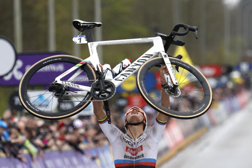 FILE - Netherland's Mathieu van der Poel holds his bike up at the finish line after taking first place in the Tour of Flanders in Oudenaarde, Belgium on March 31, 2024. World champion Mathieu van der Poel will focus on the Olympic road race at the Paris Games this summer after the Tour de France, skipping mountain biking. The versatile Dutch racer said on Wednesday that combining the Tour and the Olympic road race is “the most logical” choice. (AP Photo/Geert Vanden Wijngaert, File)