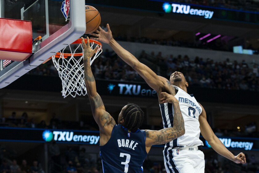De'Anthony Melton (0), de los Grizzlies de Memphis, bloquea un intento del base Trey Burke, de los Mavericks de Dallas, en juego de NBA el sábado 4 de diciembre de 2021, en Dallas. (AP Foto/Sam Hodde)