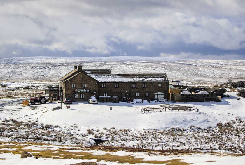 FILE - The Tan Hill Inn, following fresh snow fall, in Richmond, Yorkshire Dales, England, Saturday March 13, 2021. Customers who stopped for a drink at Britain’s highest pub got a longer stay than they bargained for, after the building was cut off by a blizzard. Some 61 people woke up Monday, Nov. 29, 2021 after their third night at the Tan Hill Inn in the Yorkshire Dales, 270 miles (435 kilometers) north of London. They have been unable to leave since Friday, when a late autumn storm brought snow and heavy winds that felled power cables and blocked roads. (PA via AP, File)