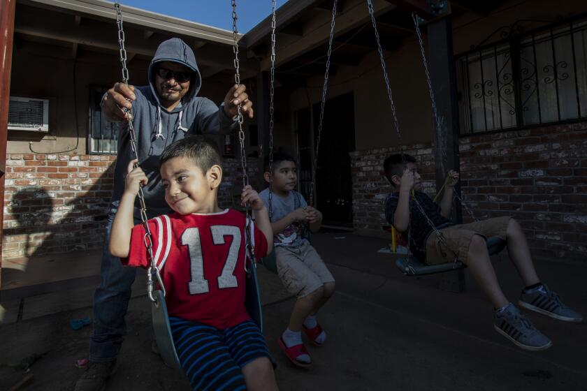 STOCKTON, CA - OCTOBER 14, 2020: Farmworker Jose Luis Hernandez spends time with his sons Carlos, 2, Jose, 6, and Angel,9 outside their apartment on October 14, 2020 in Stockton, California. In normal times, Hernandez would have saved enough money from picking summer fruit in the California fields to make it through the slow winter months, but because of pandemic, his wages were cut and he isn't sure how he will provide food and shelter for his wife and three sons as the final grapes are taken from the vines. He's had to borrow money from a friend."I haven't saved anything. I am worried, " he said.(Gina Ferazzi / Los Angeles Times)