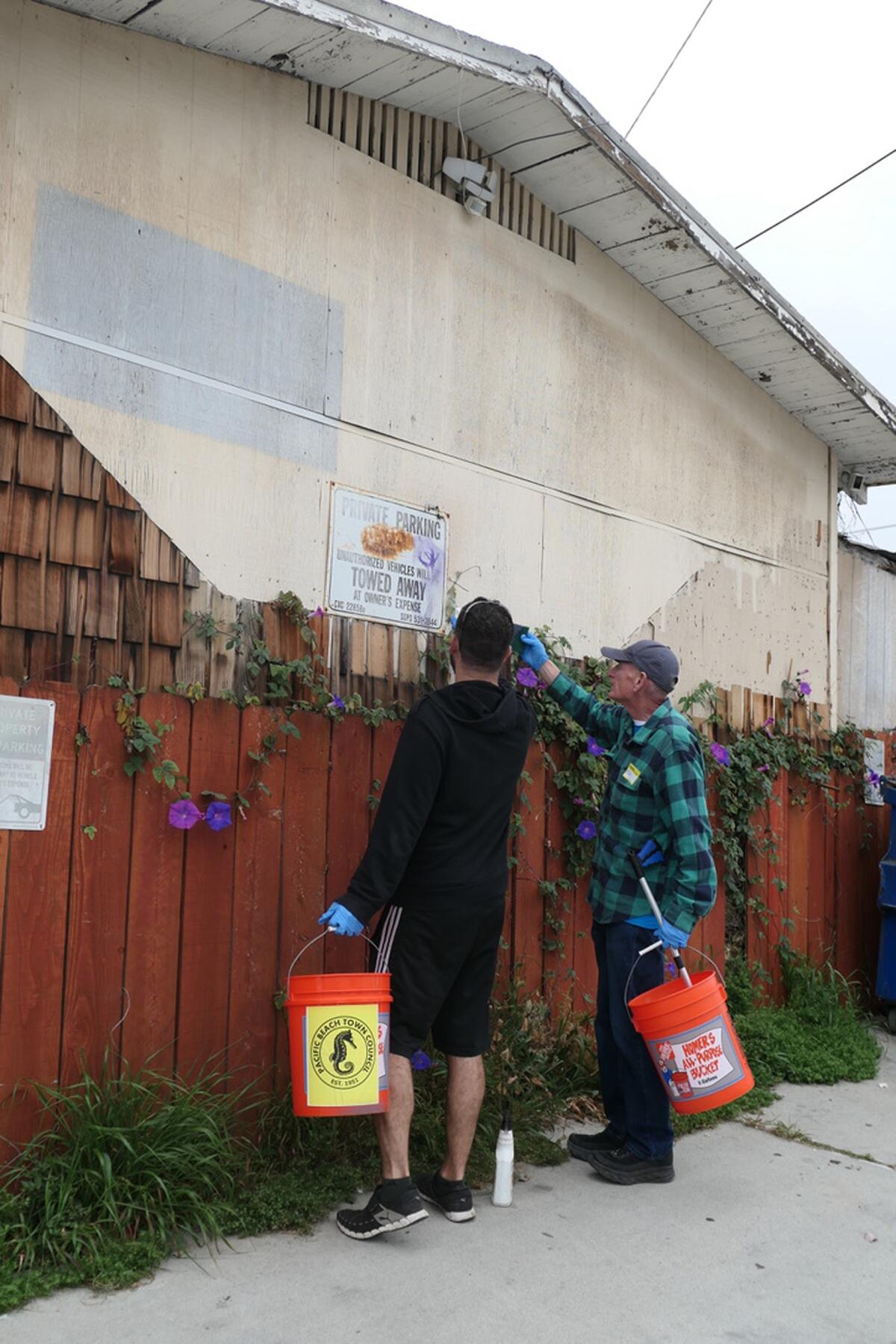 Volunteers Arash Bahar and Ed Maxwell removing graffiti in Pacific Beach on May 13.