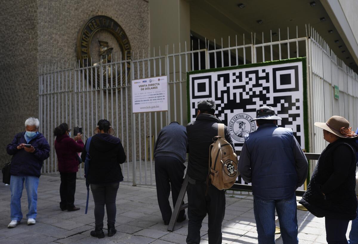 Varias personas miran un código QR afuera del Banco Central de Bolivia 