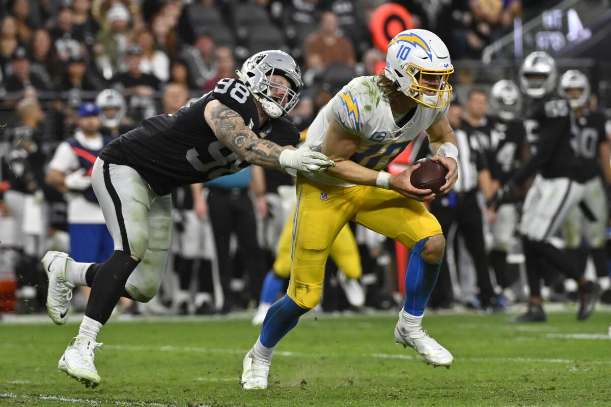 Chargers quarterback Justin Herbert tries to scramble away from Raiders defensive end Maxx Crosby (98) in the second half.