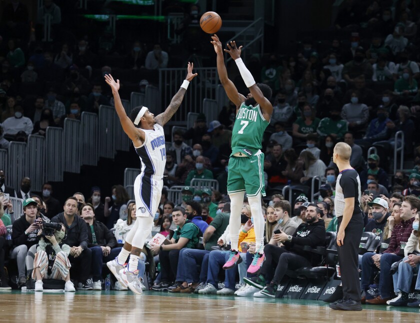 Boston Celtics guard Jaylen Brown (7) shoots a three-point shot over the defense of Orlando Magic guard Gary Harris (14) during the first half of an NBA basketball game, Sunday, Jan. 2, 2022, in Boston. (AP Photo/Mary Schwalm)