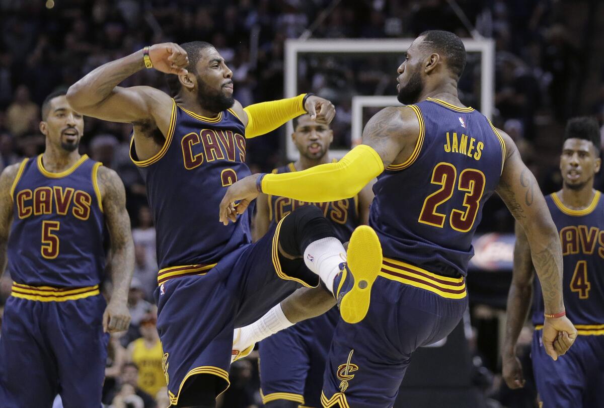 Cavaliers point guard Kyrie Irving celebrates with forward LeBron James after making a shot during an overtime victory against the Spurs on Thursday.