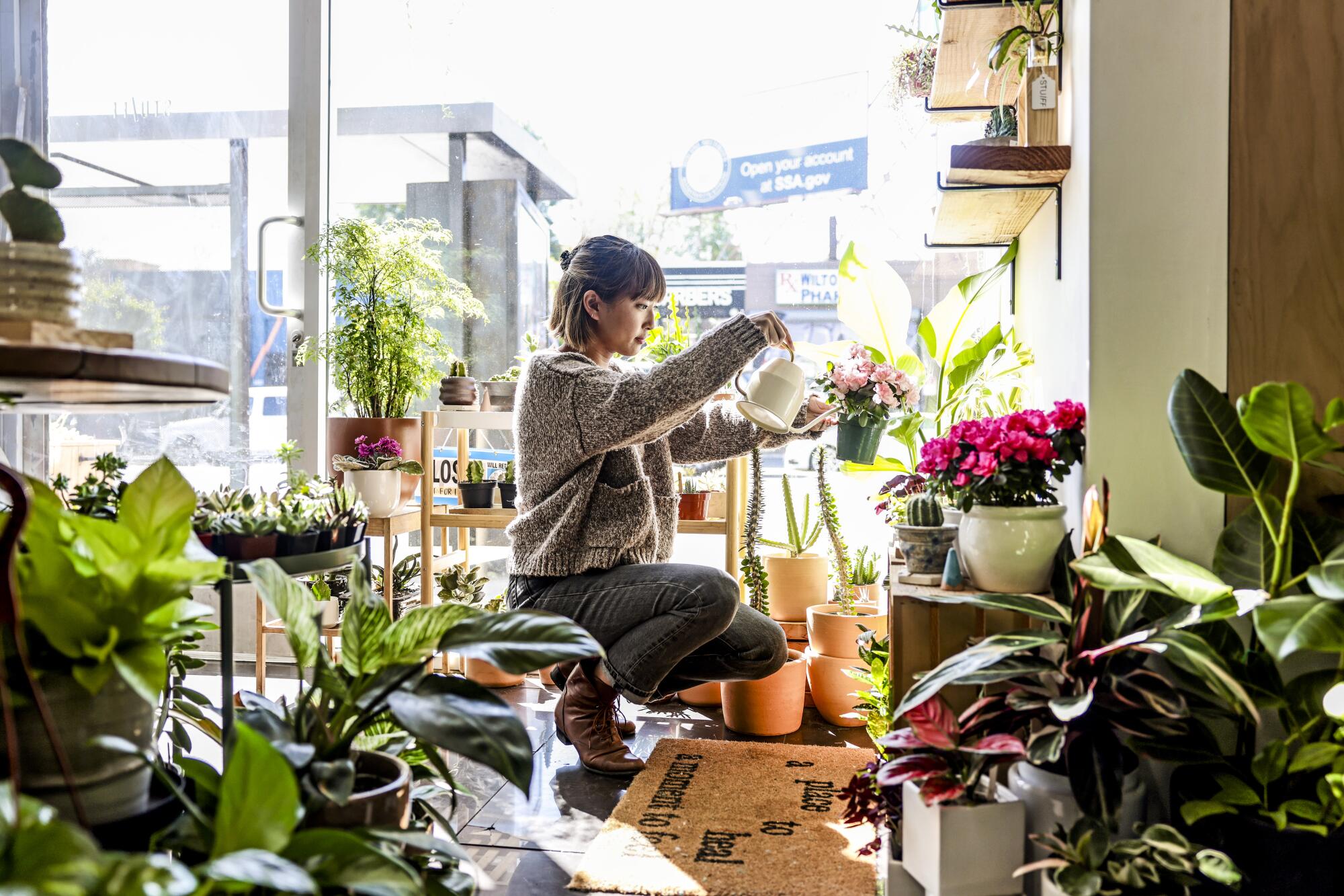 Belle Dankongkakul waters plants inside her store 