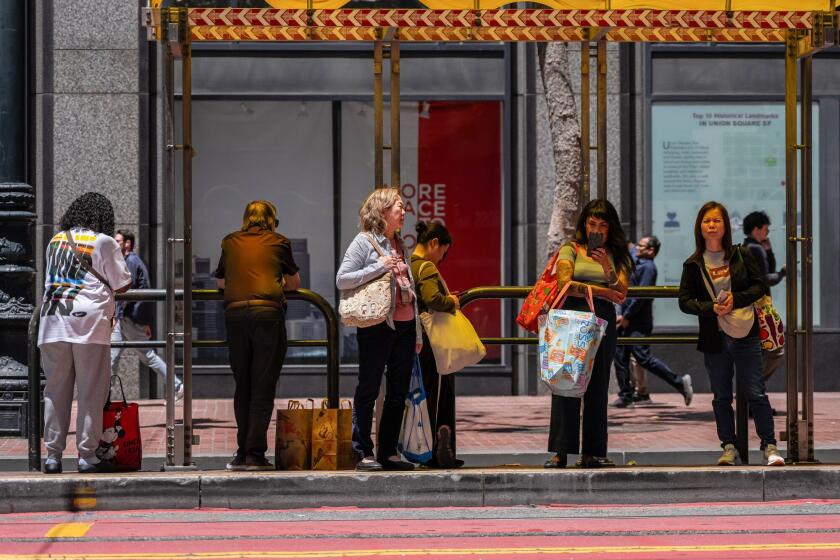 Commuters wait for a bus in San Francisco. Photographer: David Paul Morris/Bloomberg
