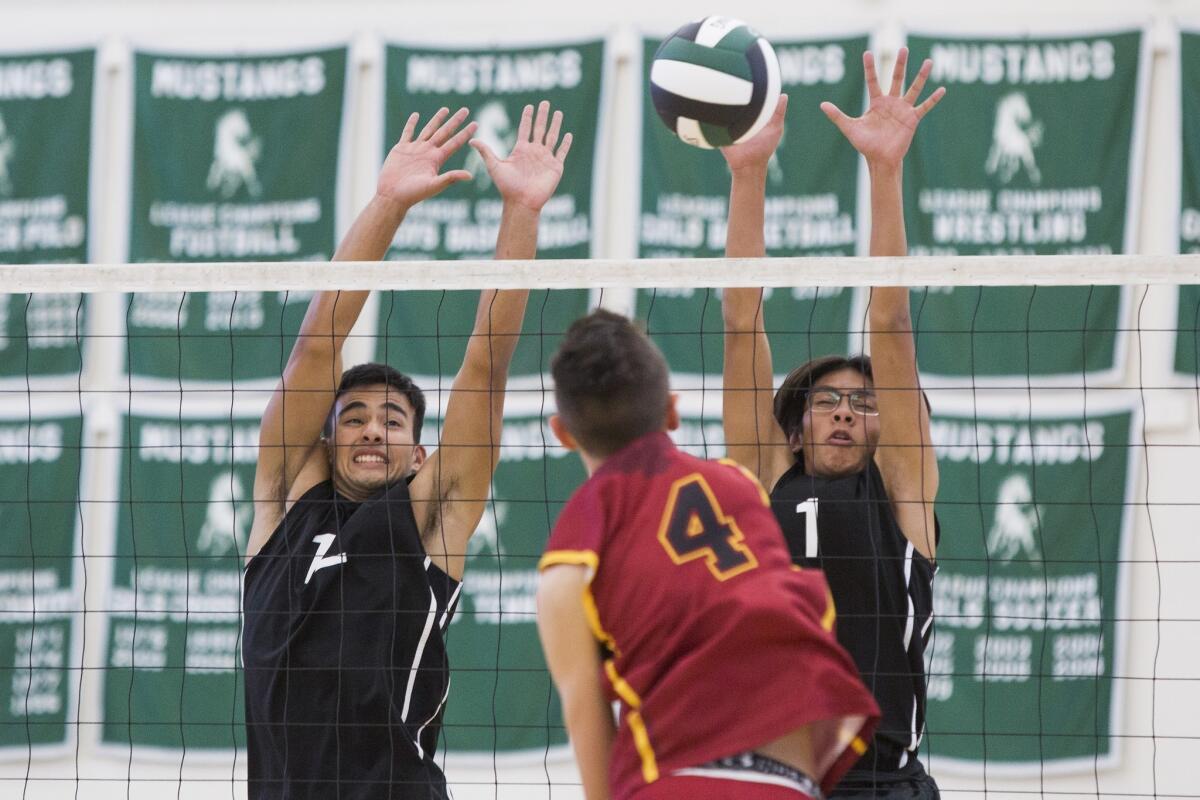Costa Mesa's Ethan Elliott, left, and Jason Chiang block a spike by Estancia during an Orange Coast League match on March 21.