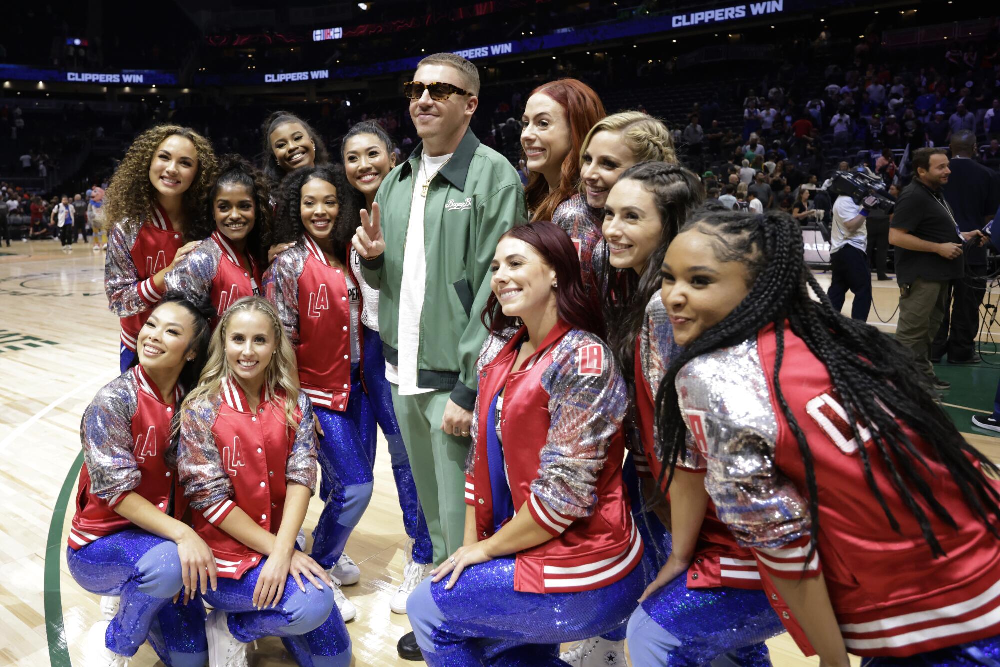 Rapper Macklemore poses with the Clippers dancers a preseason game at Climate Pledge Arena in Seattle.