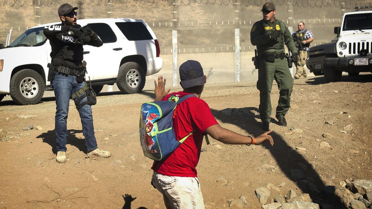 A Central American migrant is stopped by U.S. agents, who order him to go back to the Mexican side of the border, after a group of migrants got past Mexican police.