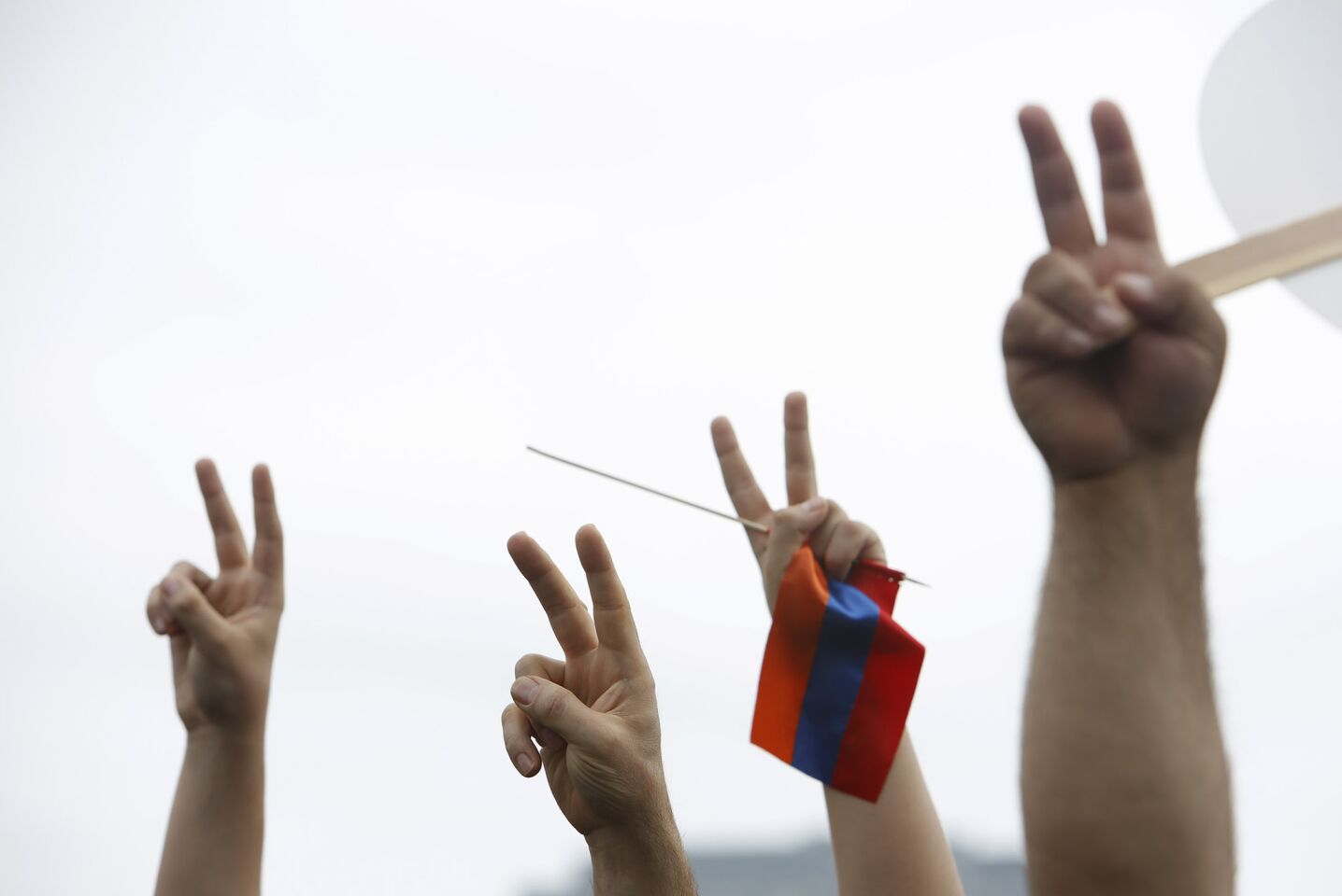 Peace signs are held, along with a small Armenian flag, during the rally.