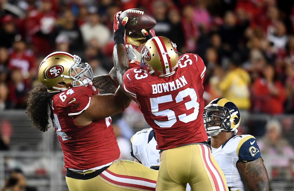 The San Francisco 49ers' Mike Purcell, left, and NaVorro Bowman reach for a deflected pass by Rams quarterback Case Keenum in a game last season. Bowman came up with the interception.