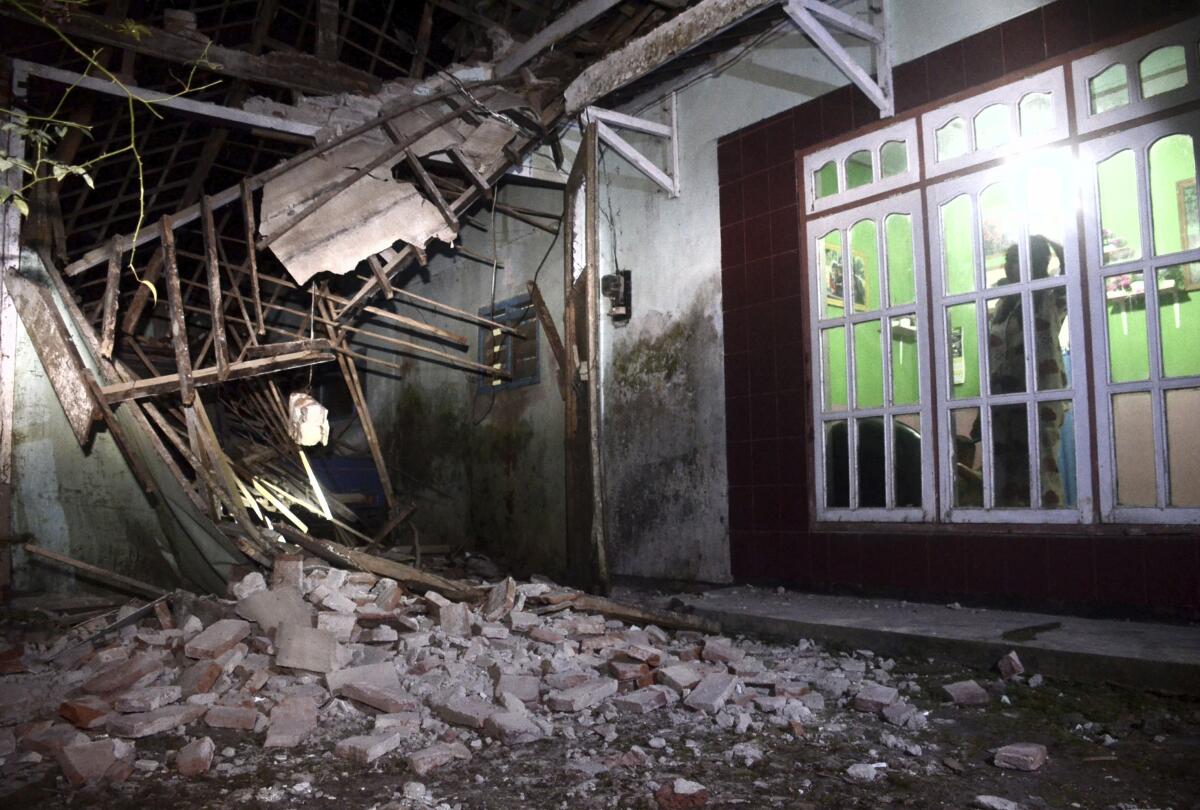 Una mujer inspecciona parte de su casa dañada por un sismo en Malan, en Java Orienal, Indonesia