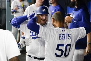 Los Angeles Dodgers' Max Muncy celebrates in the dugout with Mookie Betts (50) after hitting a home run.