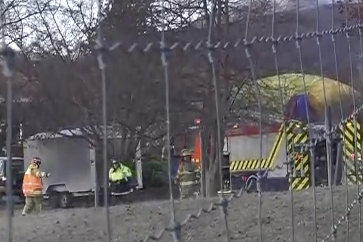 In this image made from video, rescue crews tend to a hot air balloon crash near Arrowtown, New Zealand, Friday, July 9, 2021. The balloon crashed as it was about to land on Friday, injuring all 11 people on board, including two who suffered serious injuries and were airlifted to a hospital, according to authorities and the ballooning company. (TVNZ via AP)