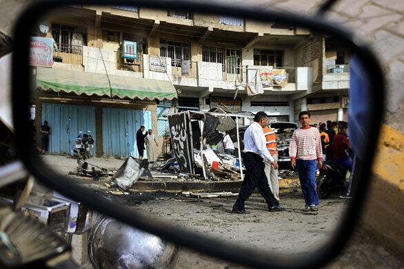 Iraqis are reflected in the mirror of a motorcycle as they gather at the scene of a car bombing on the outskirts of Baghdad's impoverished Shiite suburb of Sadr City. According to security sources, one person was killed and four others were wounded in the blast.