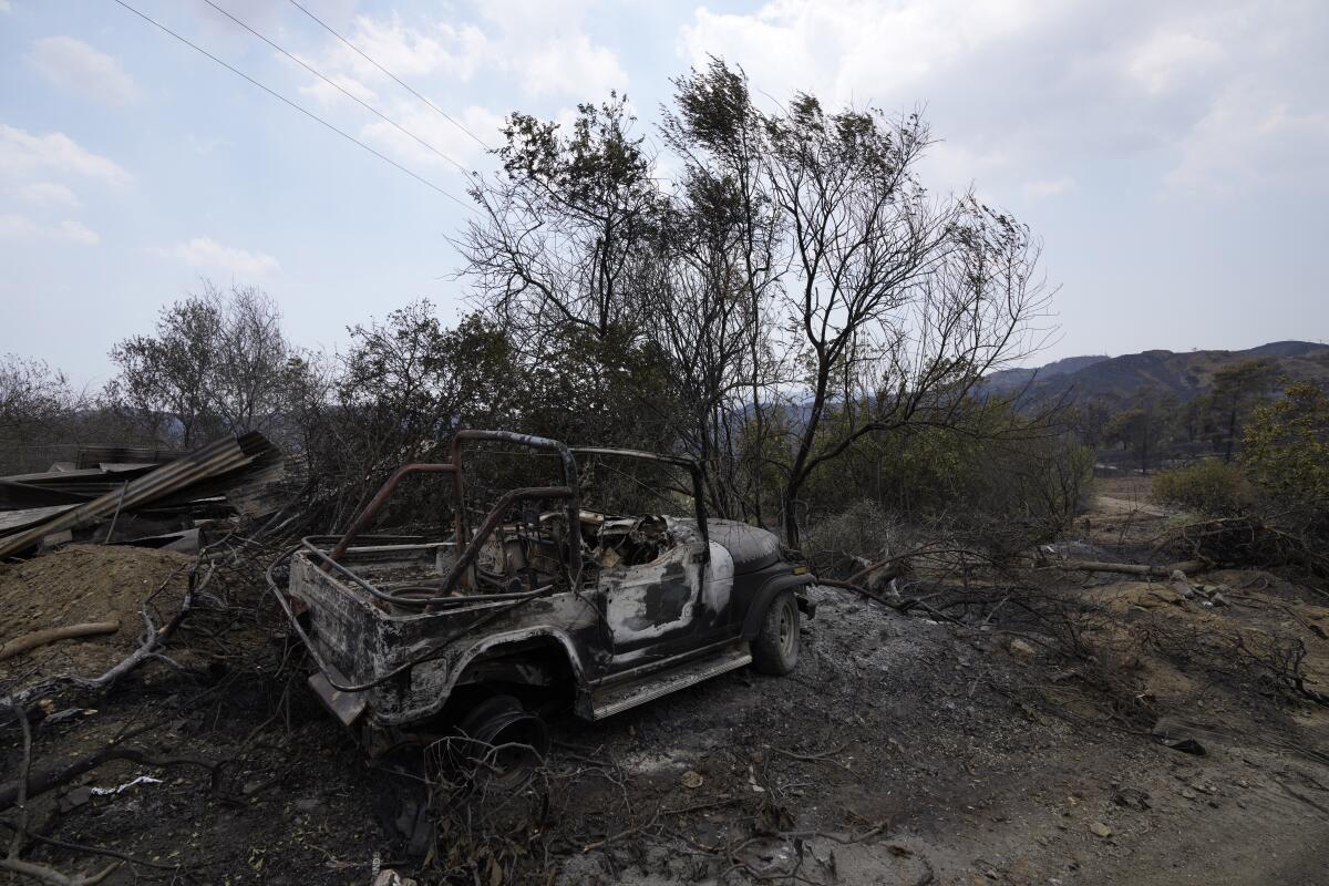 A burned car is seen on Troodos mountain, in Ora village, southwestern Cyprus, Sunday, July 4, 2021. Cyprus search crews discovered the bodies of four people outside a fire-swept mountain village on Sunday in what a government minister called the "most destructive" blaze in the east Mediterranean island nation's history. (AP Photo/Petros Karadjias)
