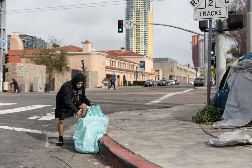 Jay Espinoza, 19, picks up trash by a homeless encampment in downtown San Diego.