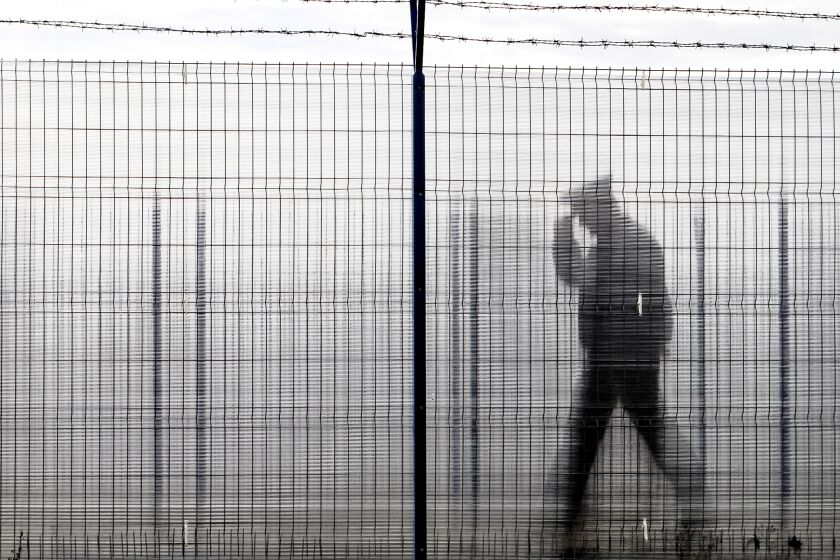 ARCHIVO - Un policía de fronteras rumano, visto a través de una cerca de plástico, patrulla en un paso fronterizo entre Rumanía y Moldavia, en Ungheni, Rumanía, el 18 de enero de 2011. (AP Foto/Vadim Ghirda, Archivo)