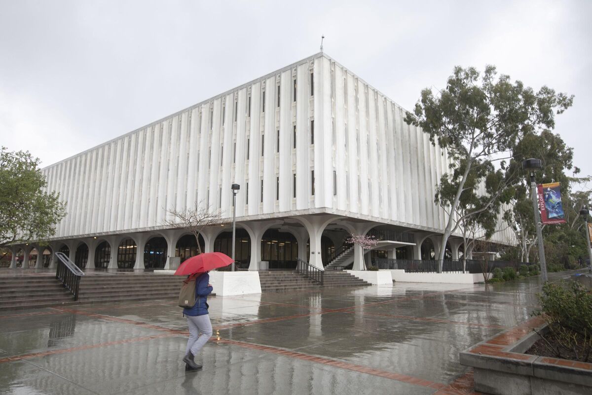A student with an umbrella walks through the San Diego State campus