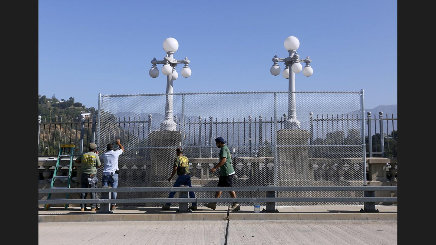 Workers from Western Fence Company place 1-inch safety chain link mesh around one of 20 alcoves on the Colorado Street Bridge in Pasadena on Saturday, July 23, 2017. The fences surrounding the alcoves are being installed as a temporary measure to prevent suicide jumpers from having easy access to jump, according to City of Pasadena Dept. of Public Works capital projects manager Hayden Melbourn, P.E.